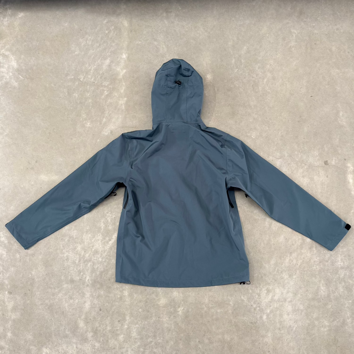 Blue jacket with black zipper on a gray concrete floor