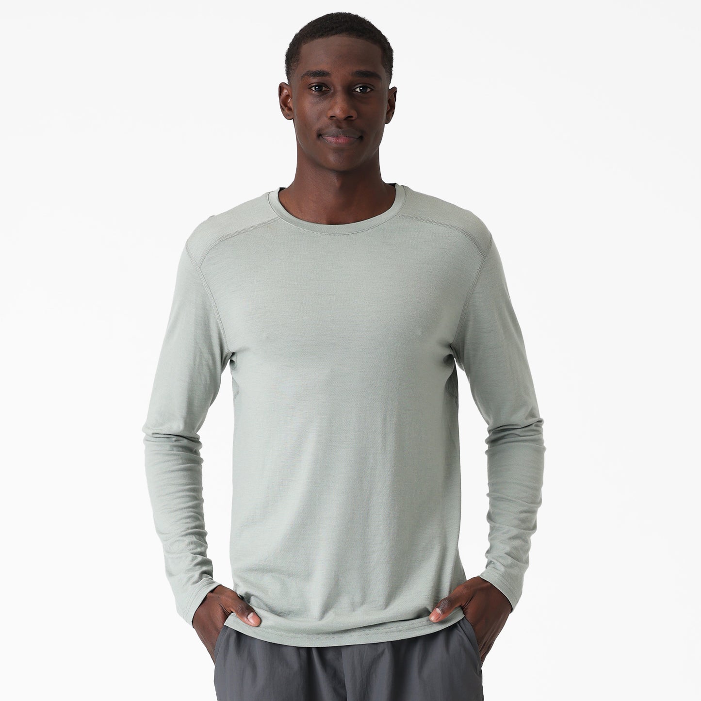 Man wearing a light green long-sleeve shirt on a white background