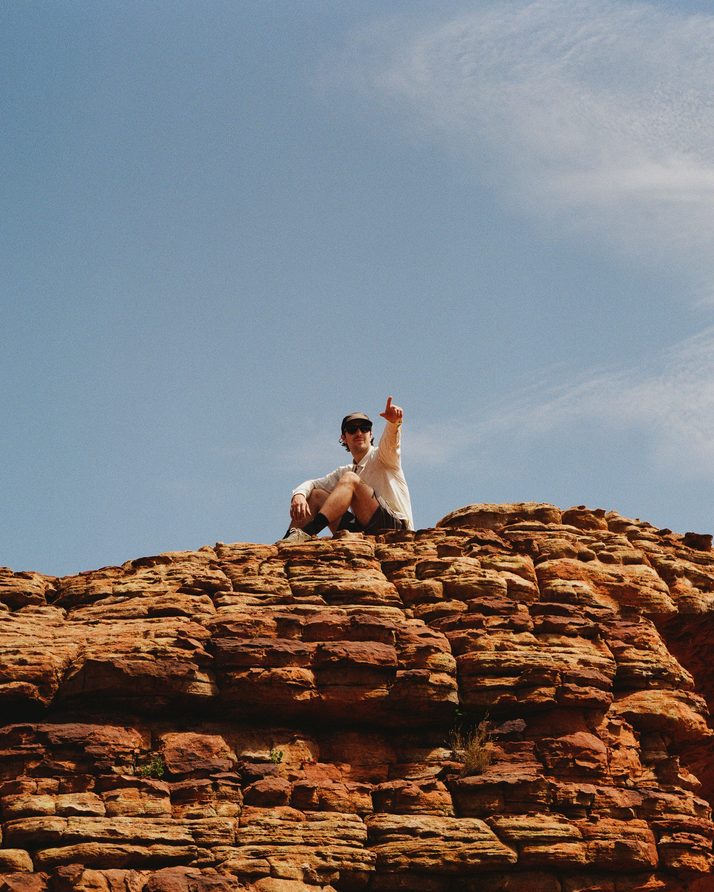 A hiker on top of a sandstone dome at Kings Canyon against a blue sky