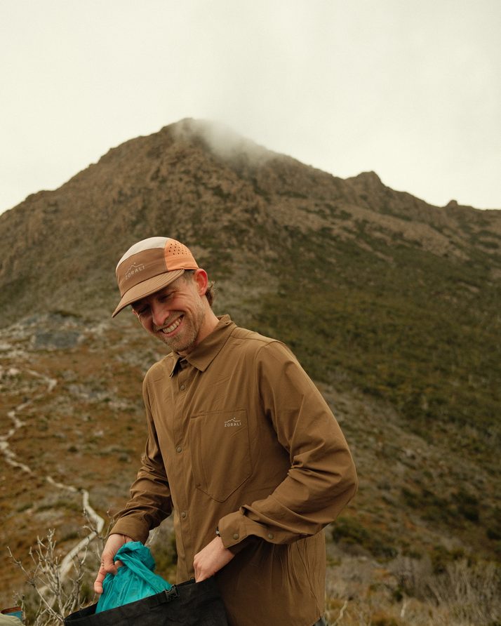 Cam smiling as he packs up at a summit stop in the Teak Daylight™ Technical Long Sleeve Shirt