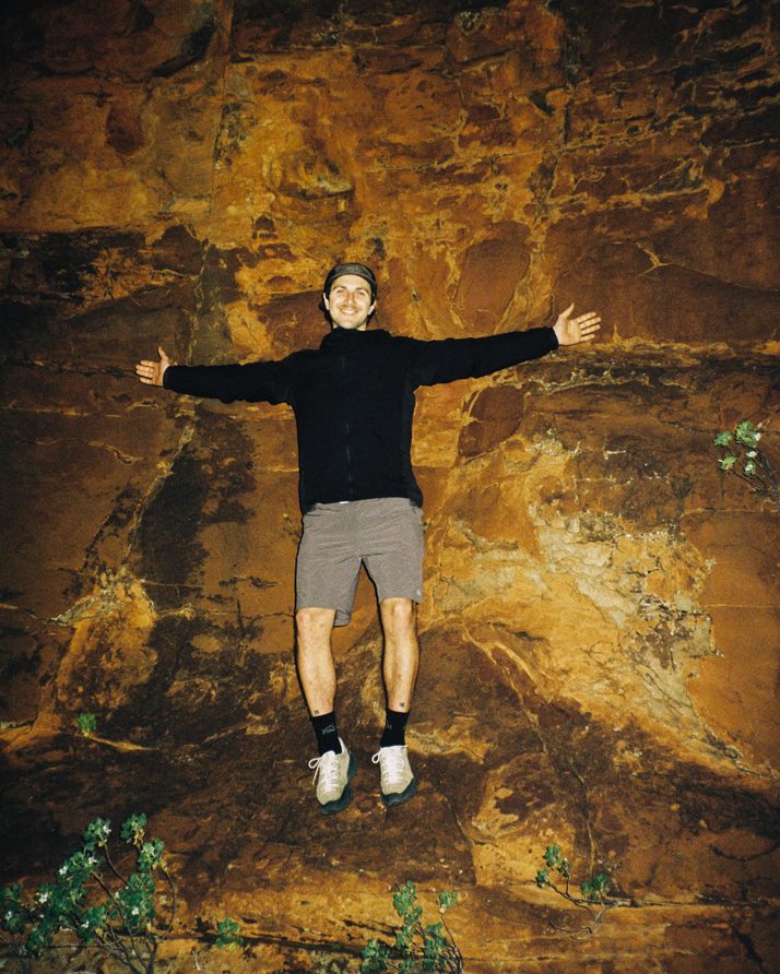 Hiker with arms out in a glowing rock cave