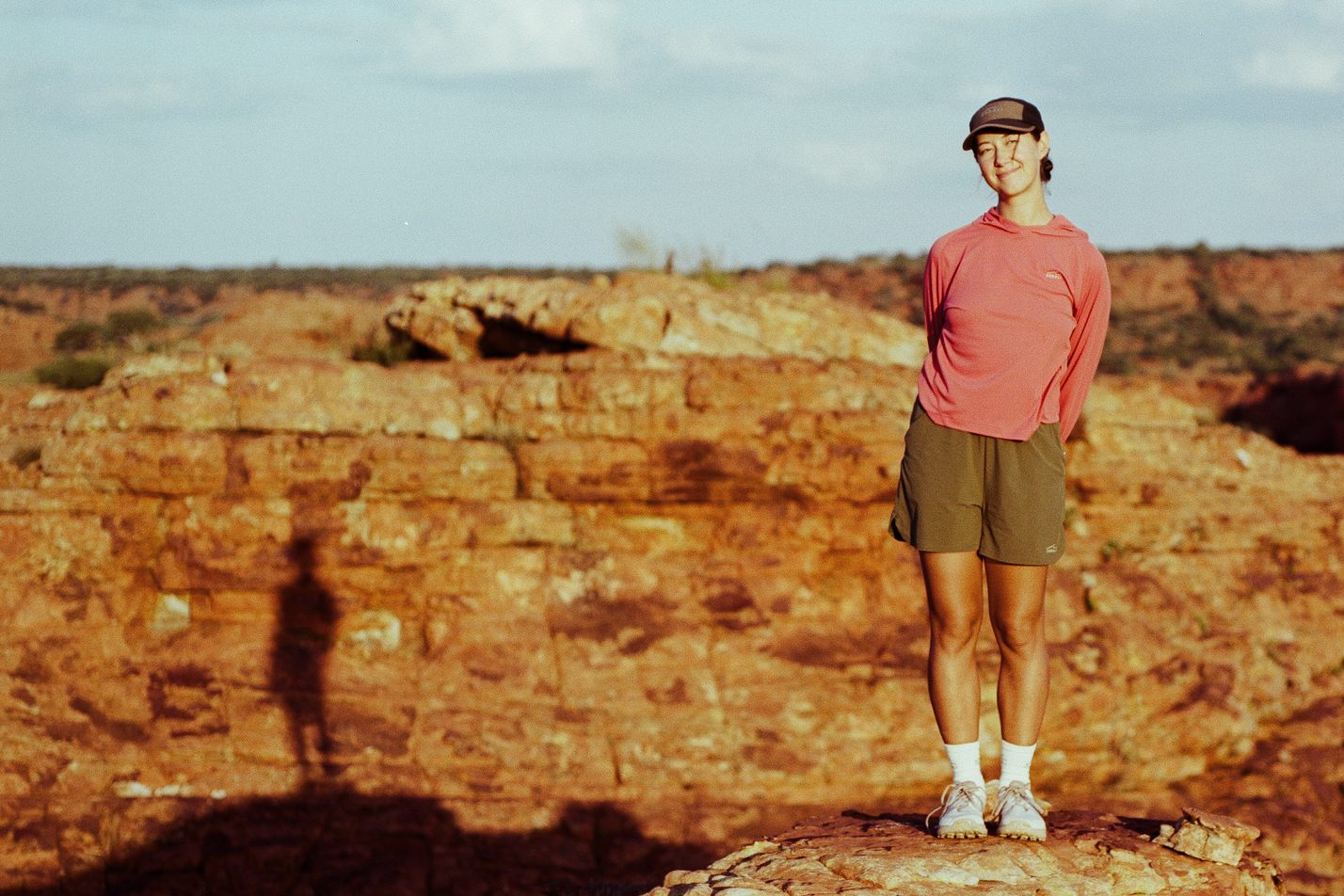 A hiker on a sandstone dome at Kings Canyon, a long shadow across the rock