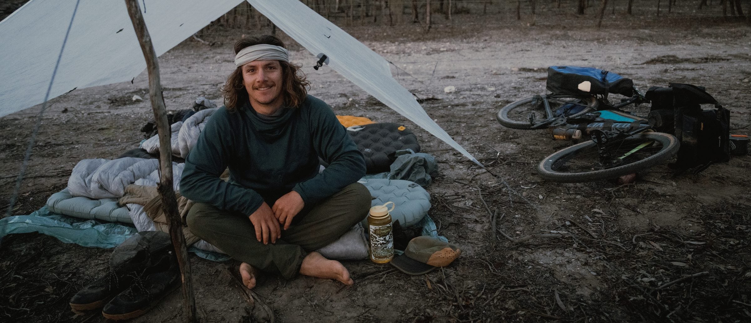 Daygin at camp under the tarp on his 13-day ride, in his Air-Grid Fleece