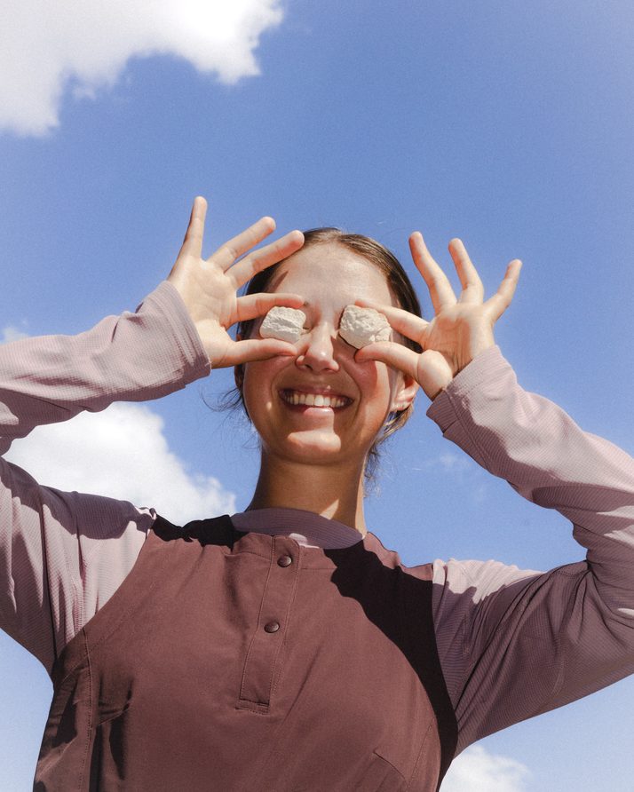 Hiker holding two stones over her eyes in the Daylight™ Motion Dress in Cacao