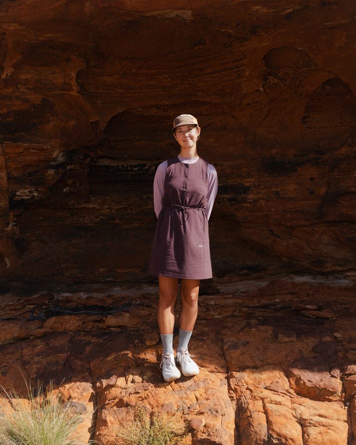 Hiker standing in a wide sandstone cave in the Daylight™ Motion Dress in Cacao