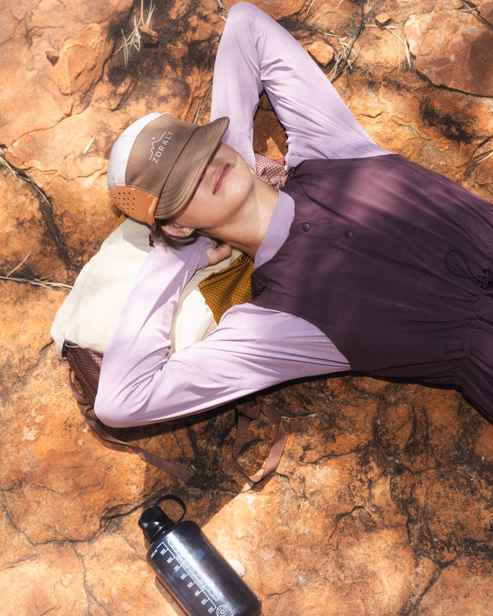 Hiker lying back on red rock in the Daylight™ Motion Dress in Cacao