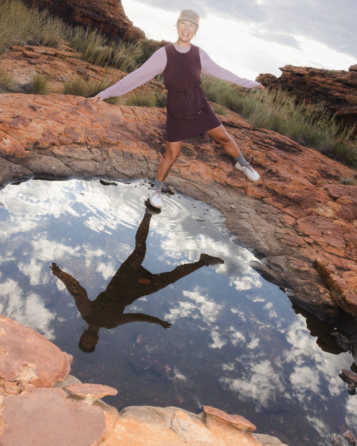 Hiker leaping over a rock pool in the Daylight™ Motion Dress, reflected in the water