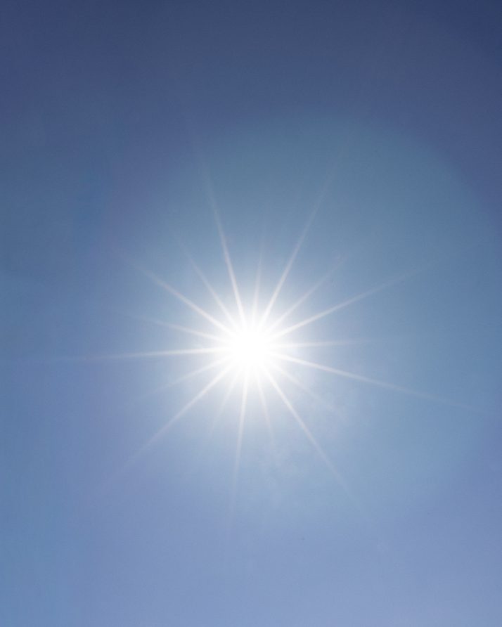 The sun bursting through a clear blue sky over Kings Canyon