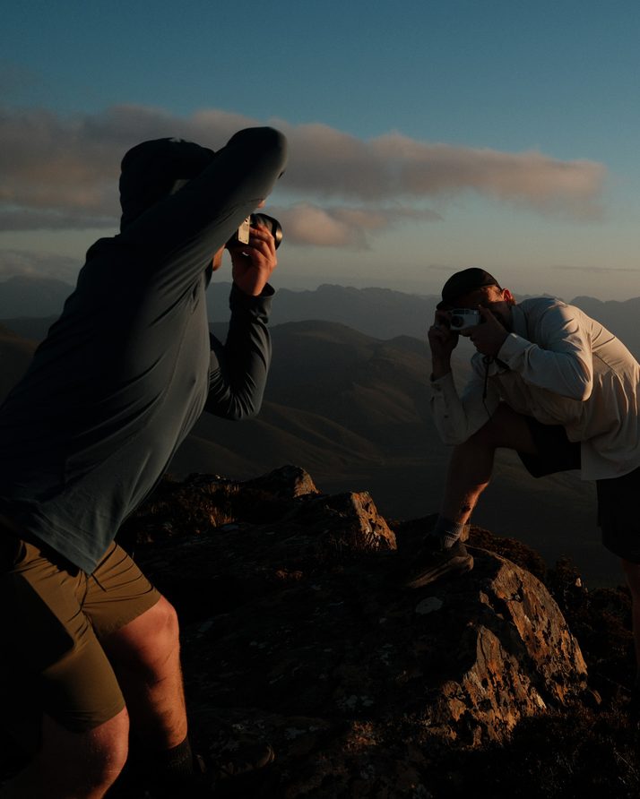 Two hikers photographing the sunset from the summit