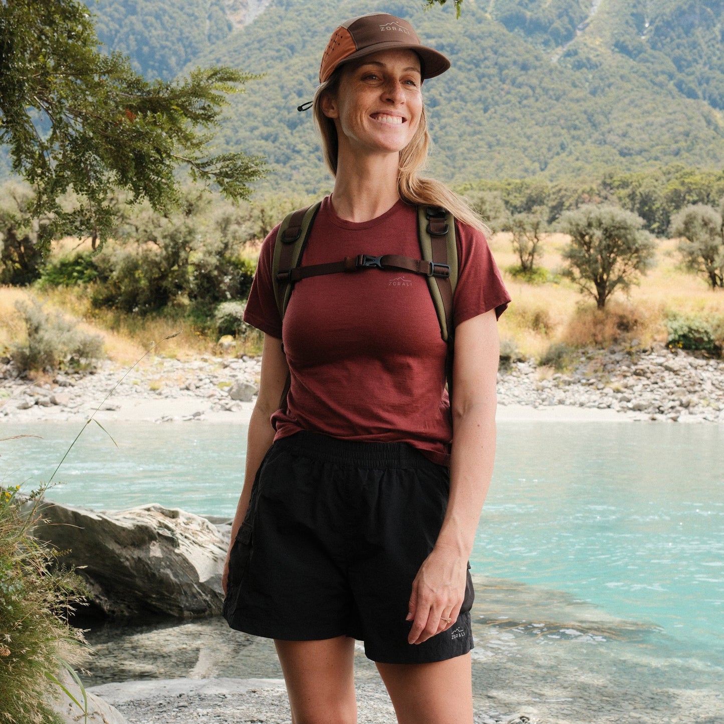 Woman hiking by a river with mountains in the background