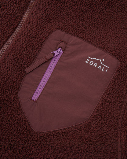 Close-up of the maroon chest pocket with purple zipper pull and Zorali logo on the Cosy Camp fleece jacket.