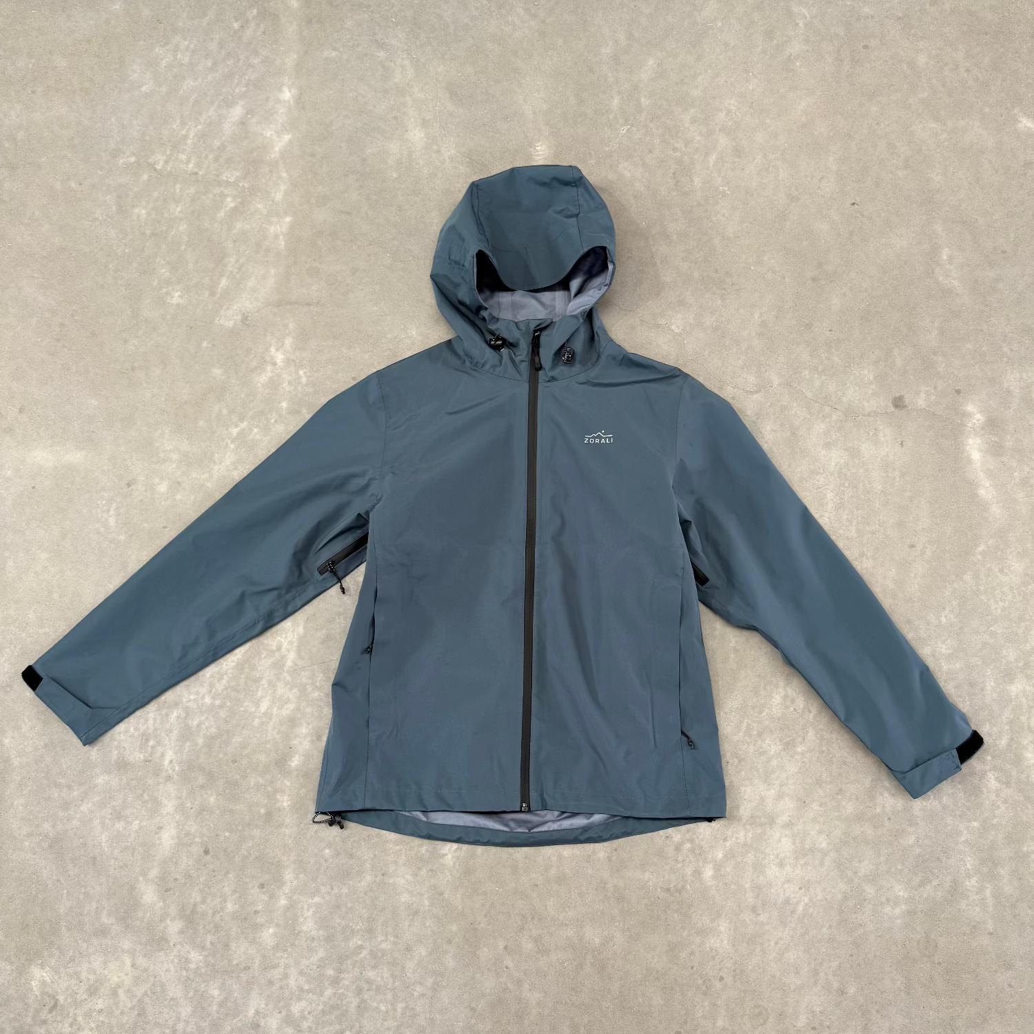 Blue jacket with black zipper on a gray concrete floor