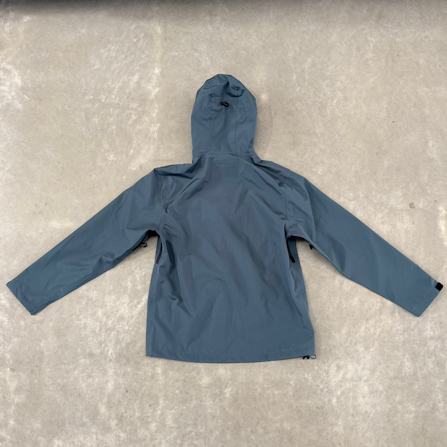 Blue jacket with black zipper on a gray concrete floor