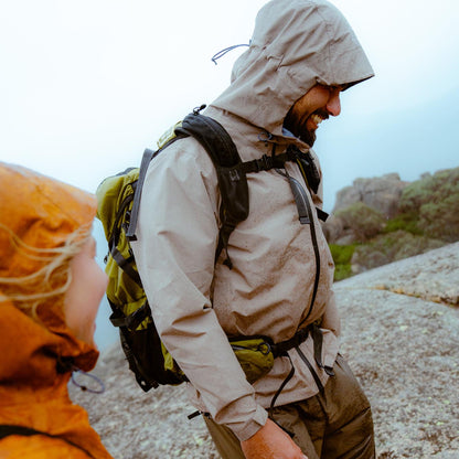 Two hikers in raincoats and backpacks on a rocky trail