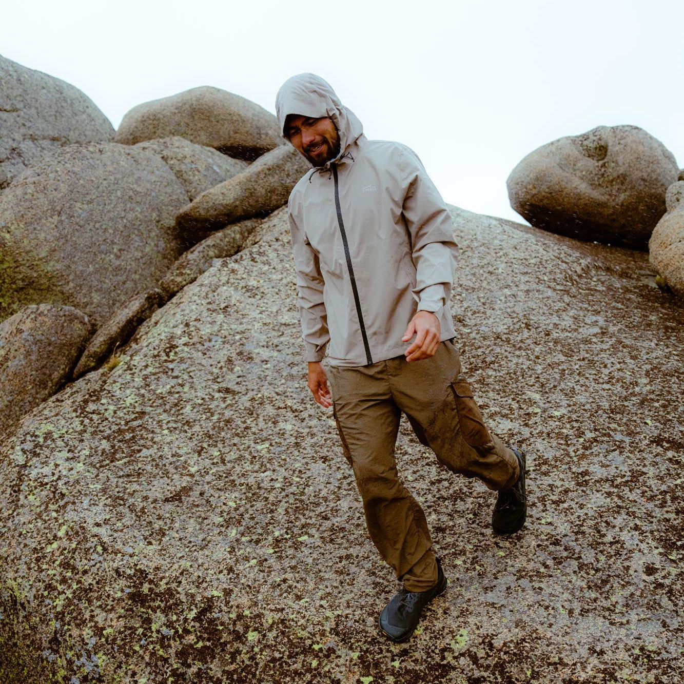 Man in a light jacket and pants standing on rocky terrain