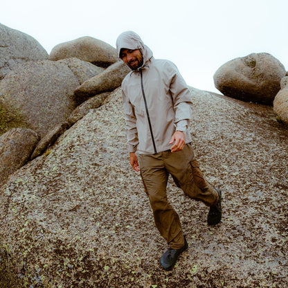 Man in a light jacket and pants standing on rocky terrain