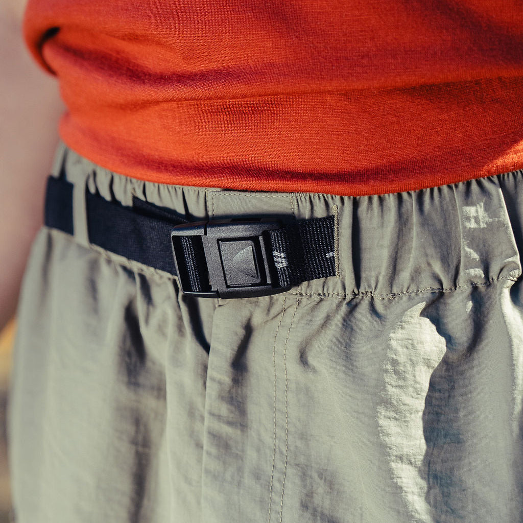 Person wearing a red shirt and green pants with a black belt.