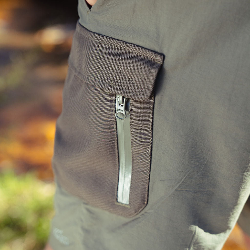 Close-up of a gray shorts with a zipper pocket against a blurred natural background
