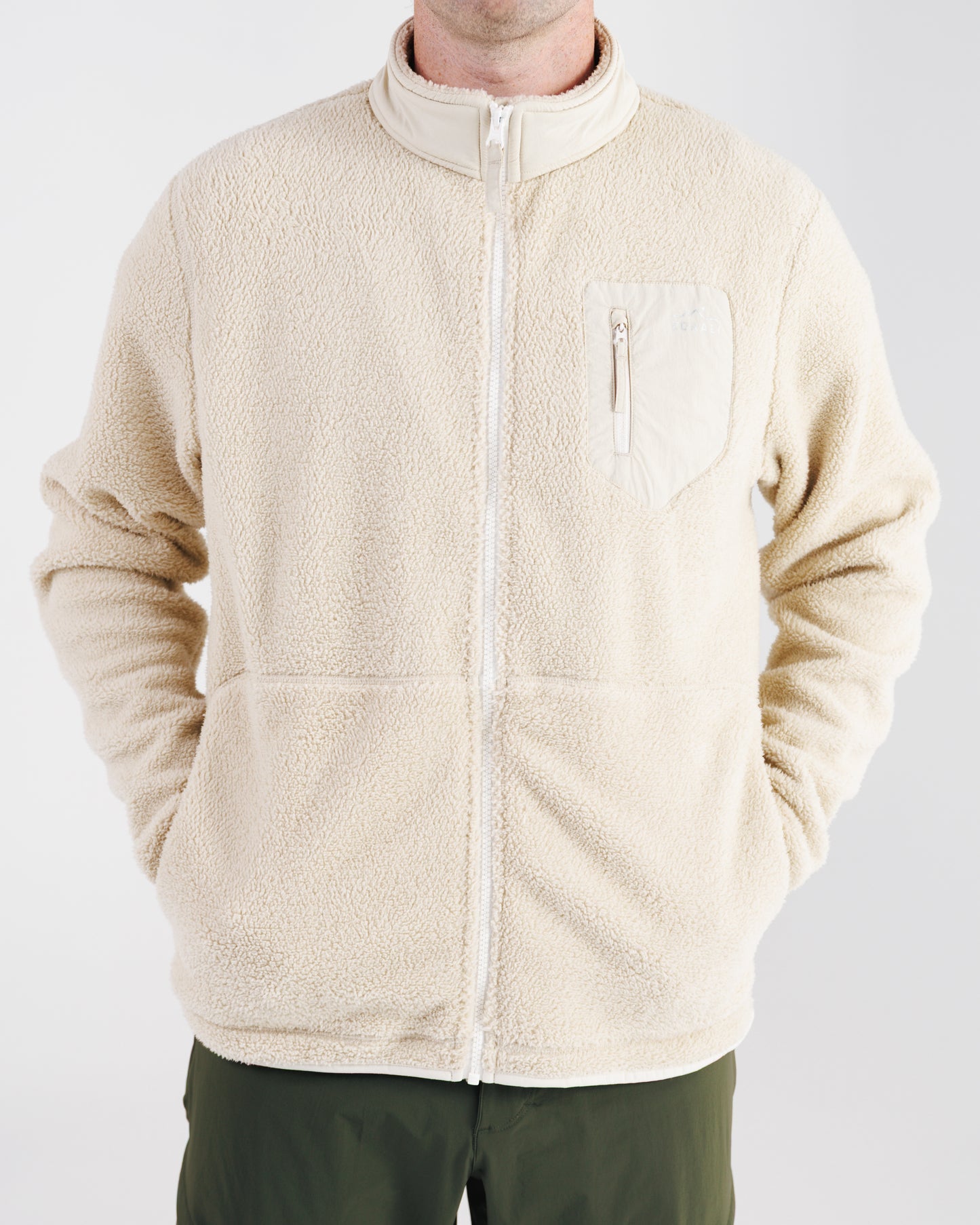 Man wearing a cream sherpa fleece zip-up jacket, front view with hands in pockets.