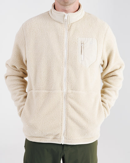 Man wearing a cream sherpa fleece zip-up jacket, front view with hands in pockets.