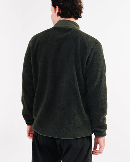 Back view of a man wearing a dark green sherpa fleece jacket with his hands at his sides.
