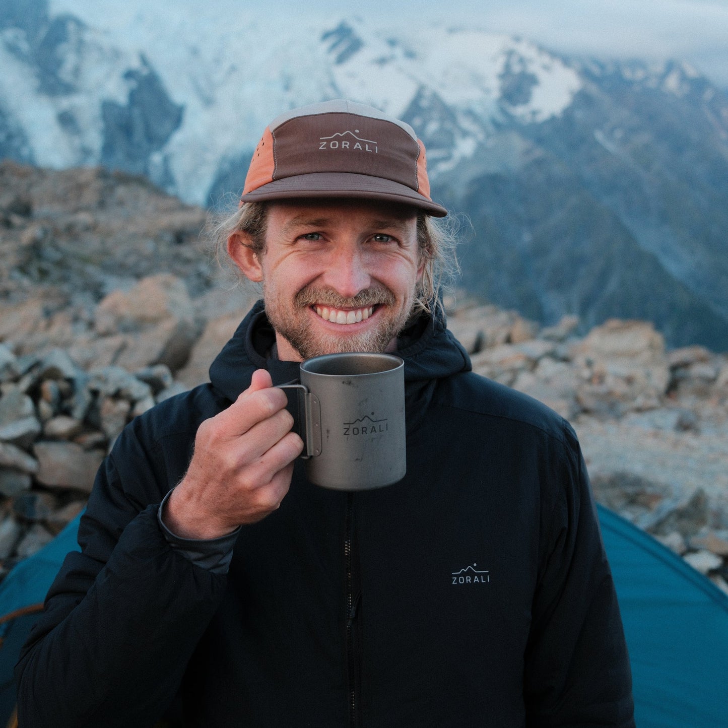 Man holding a mug with mountains in the background