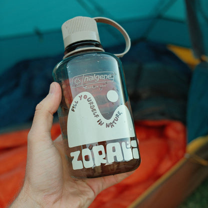 Person holding a Nalgene bottle with 'Zorai' branding in front of a tent.