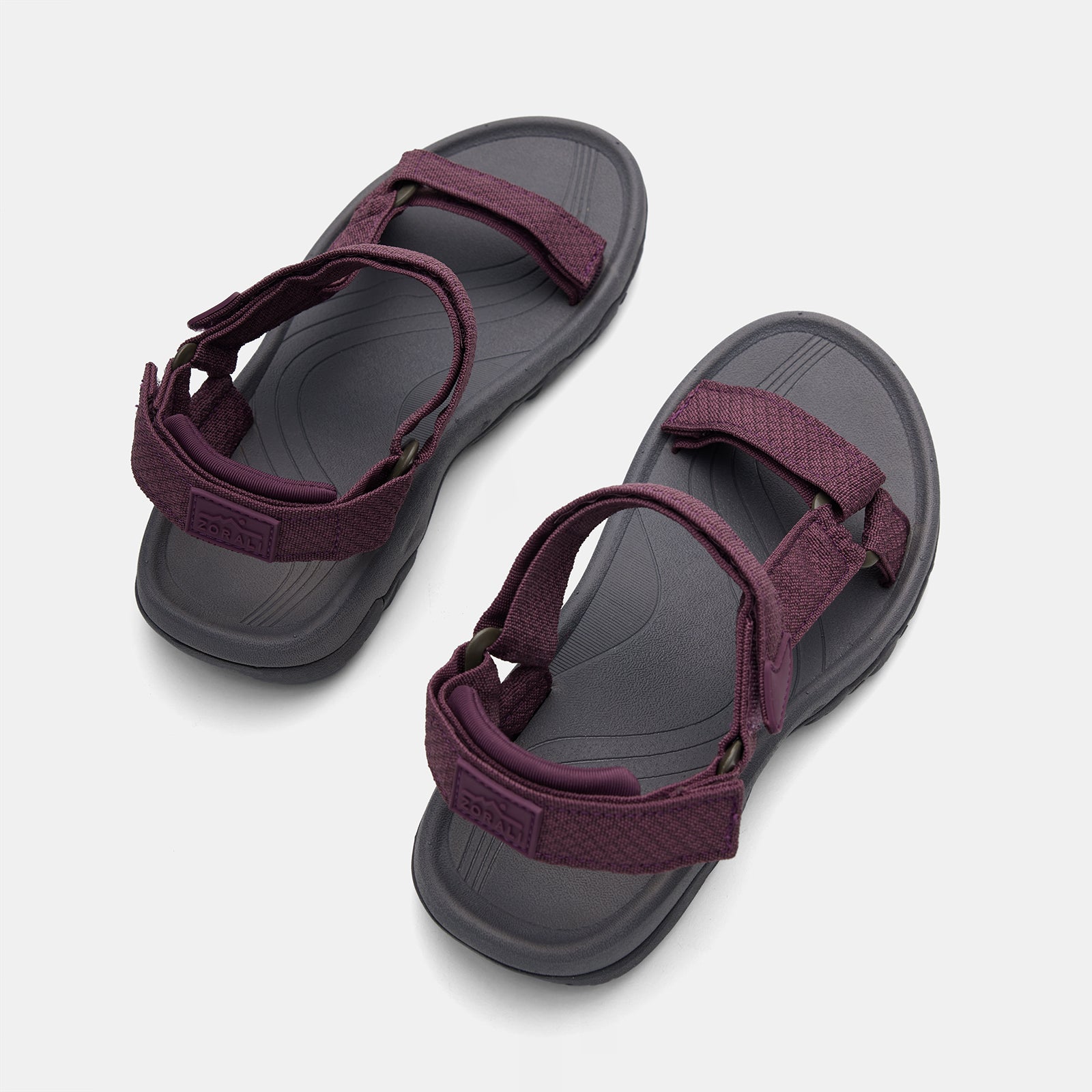 Pair of sandals with maroon straps on a light gray background