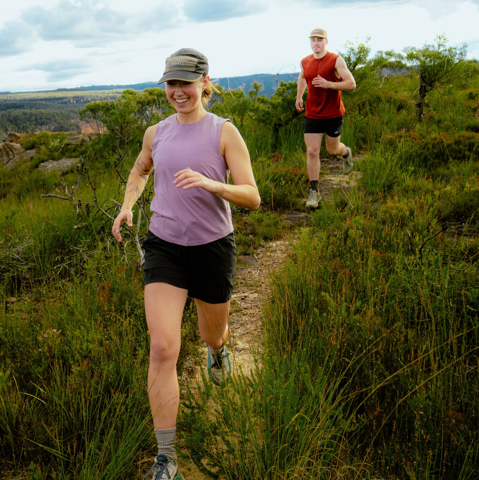 Two people running on a trail in a natural landscape