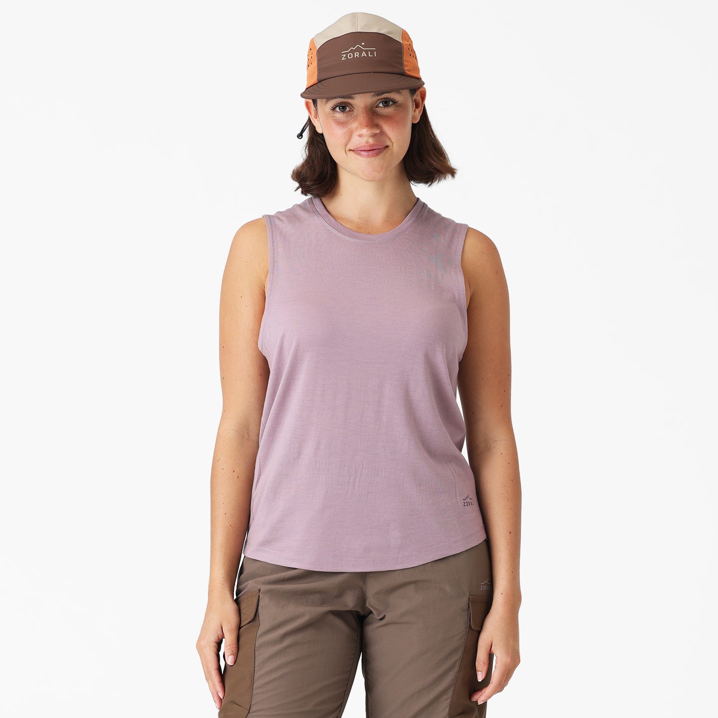 Woman wearing a sleeveless purple shirt and brown cap on a white background