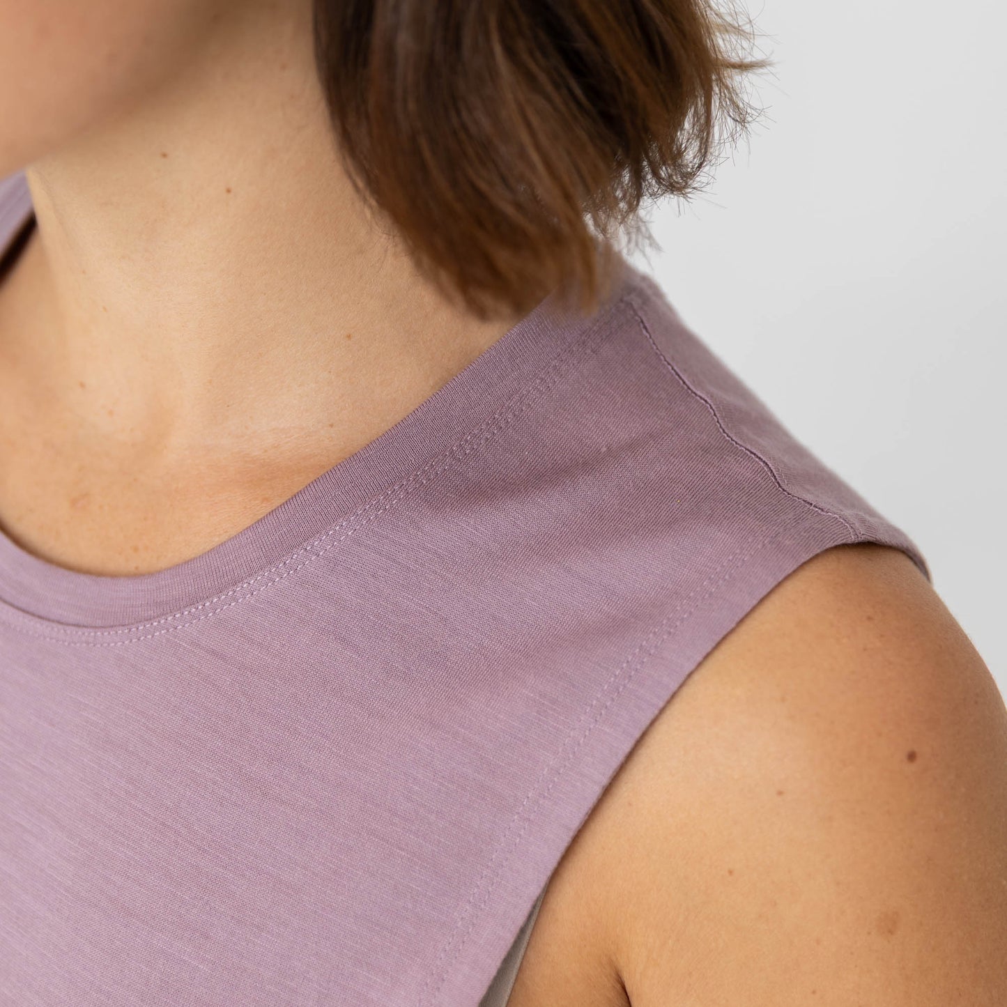 Close-up of a person wearing a light purple sleeveless top against a neutral background