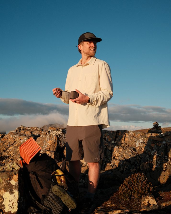 Cam at a summit stop under a blue sky in the Beachwood Daylight™ Technical Long Sleeve Shirt
