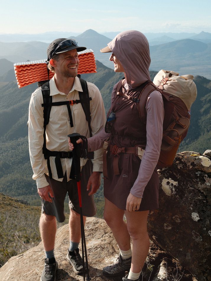Cam and Elise with their packs on a summit, Elise in the Daylight™ Motion Dress in Cacao