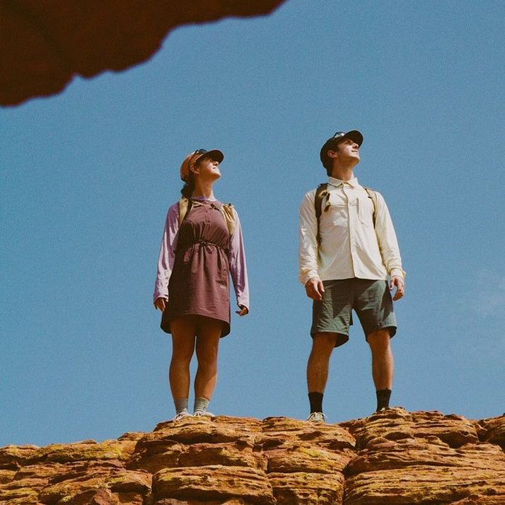 Two hikers on a sandstone ridge under a rock overhang, one in the Daylight™ Motion Dress