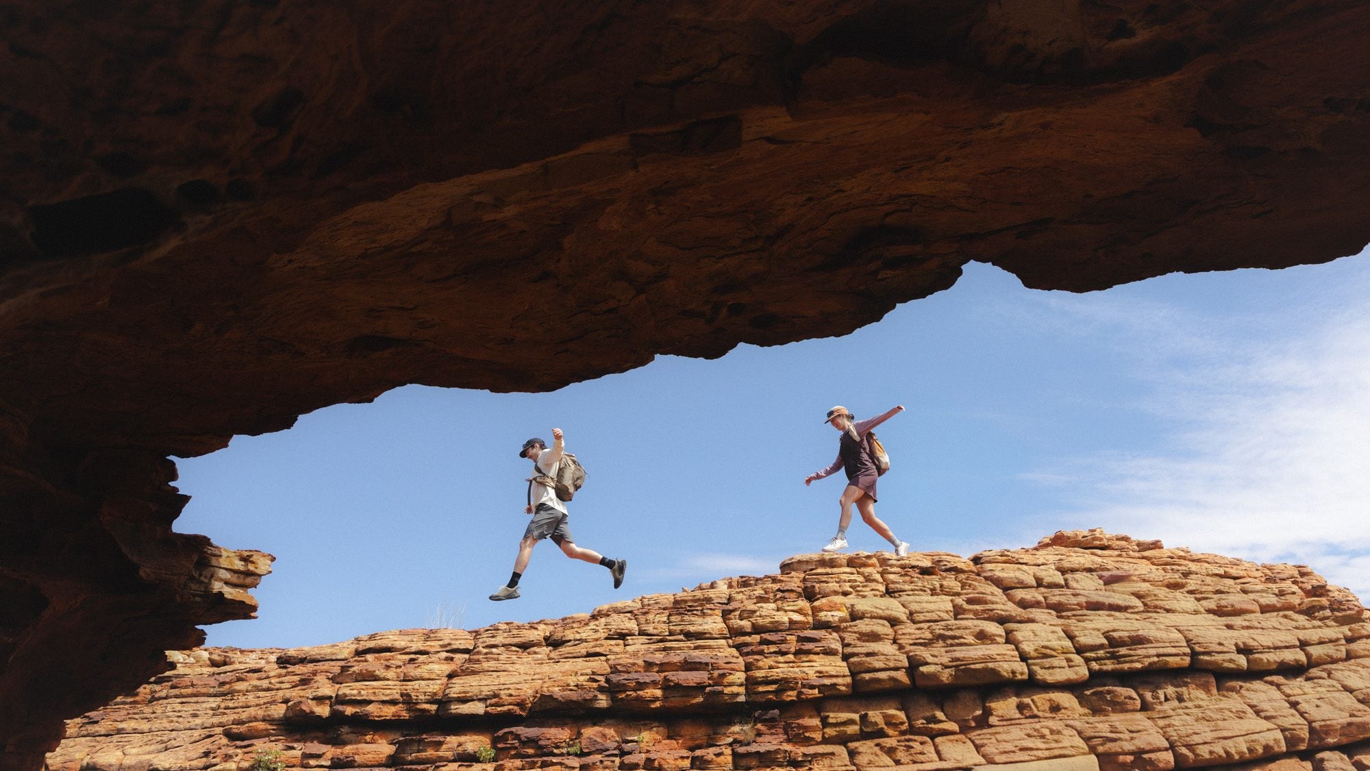 Two walkers in Daylight under a sandstone arch at Kings Canyon
